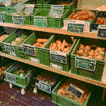 Auslage mit verschiedenen Gemüsekisten und Preisen auf Kreidetafeln